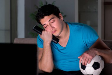 Genç adam gece geç saatlerde futbol seyrediyor.