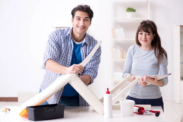 Vrouw helpen man naar reparatie kapotte stoel thuis — Stockfoto