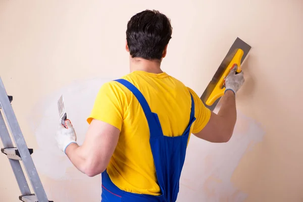 Empregado jovem empreiteiro aplicando gesso na parede — Fotografia de Stock