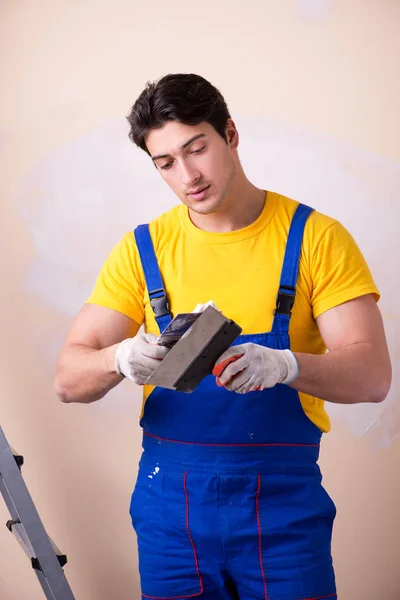 Empregado jovem empreiteiro aplicando gesso na parede — Fotografia de Stock