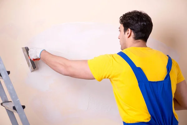 Young contractor employee applying plaster on wall