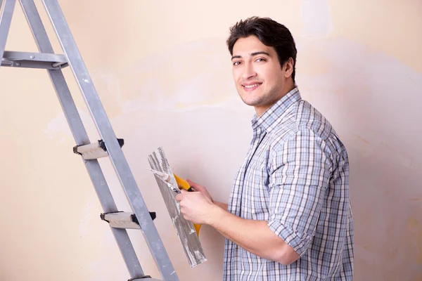 Hombre joven aplicando yeso en la pared en casa — Foto de Stock