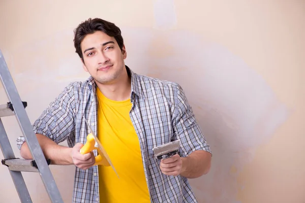 Hombre joven aplicando yeso en la pared en casa — Foto de Stock