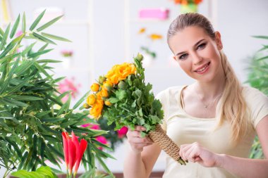 Bahçesinde çiçekleri sulayan genç bir kadın.