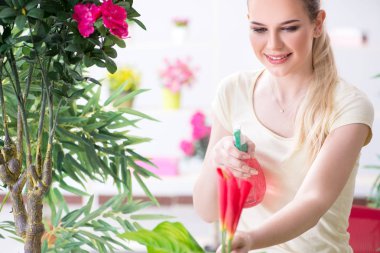 Bahçesinde çiçekleri sulayan genç bir kadın.