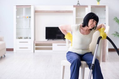 Yaşlı kadın elektrik süpürgesinden yorgun düştü.