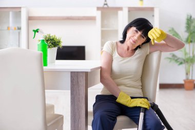 Yaşlı kadın elektrik süpürgesinden yorgun düştü.