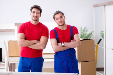 İki müteahhit personel kişisel eşyalarını taşıyor.