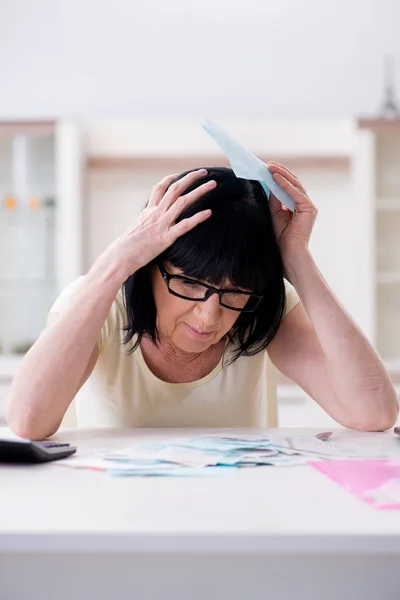 Reife Frau versucht, ihre Rechnungen unter einen Hut zu bringen — Stockfoto