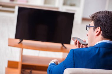 İş adamı ofiste televizyon izliyor.