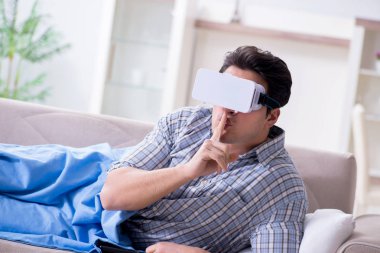 Adam evde sanal gerçeklik gözlüğü izliyor.