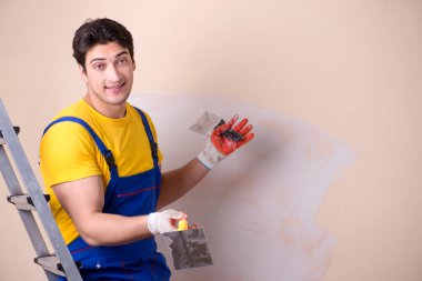 Duvara alçı yapıştıran genç müteahhit.