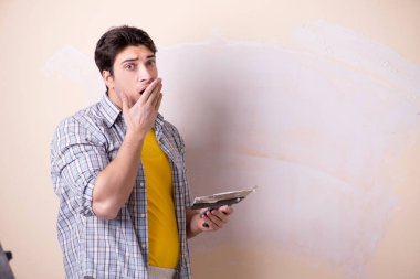 Evdeki duvara alçı yapıştıran genç adam.