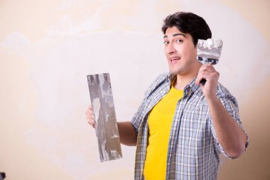 Evdeki duvara alçı yapıştıran genç adam.