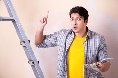 Evdeki duvara alçı yapıştıran genç adam.