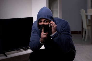 Hırsız, apartmandan televizyon çalıyor.