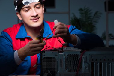 Bilgisayar uzmanı gece geç saatlerde bilgisayarı tamir ediyor.