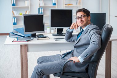 Birçok ekranın önünde oturan bir iş adamı