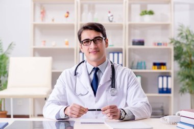 Genç doktor ofiste oturuyor.