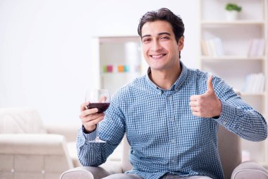 Genç adam evde şarap içiyor.