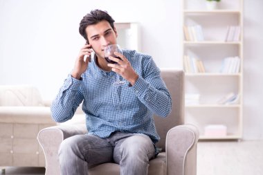 Genç adam evde şarap içiyor.