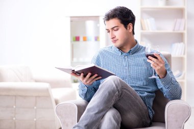 Genç adam evde şarap içiyor.