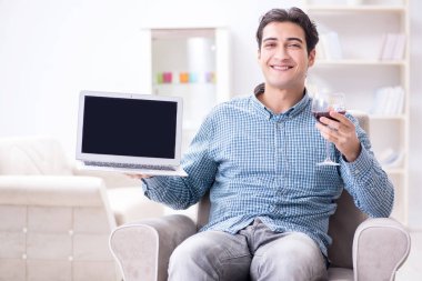 Genç adam evde şarap içiyor.