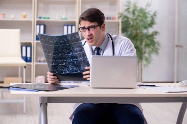 Genç doktor klinikteki röntgen görüntülerine bakıyor.