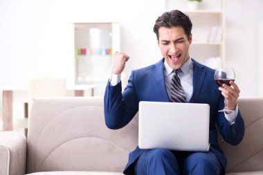 İş adamı evde oturmuş şarap içiyor.