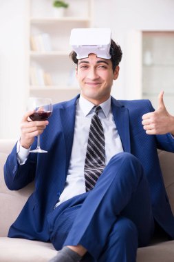 İş adamı evde oturmuş şarap içiyor.