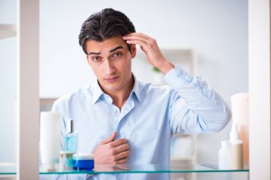 Adam banyoda çalışmak için giyiniyor.