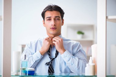 Adam banyoda çalışmak için giyiniyor.