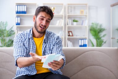 Ödeme yapması gereken faturalara kızgın bir adam.