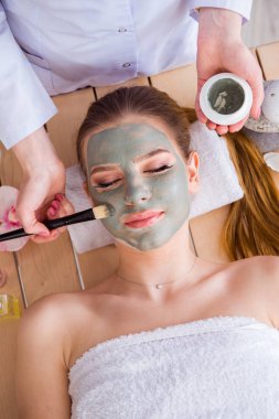 Young woman in spa health concept with face mask clipart