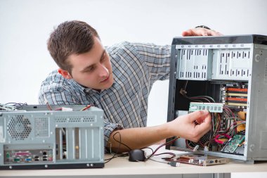 Genç teknisyen atölyede bilgisayar tamir ediyor.