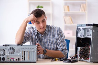 Genç teknisyen atölyede bilgisayar tamir ediyor.