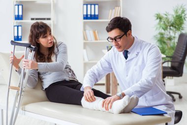 Kırık bacaklı bir hastayı muayene eden doktor.