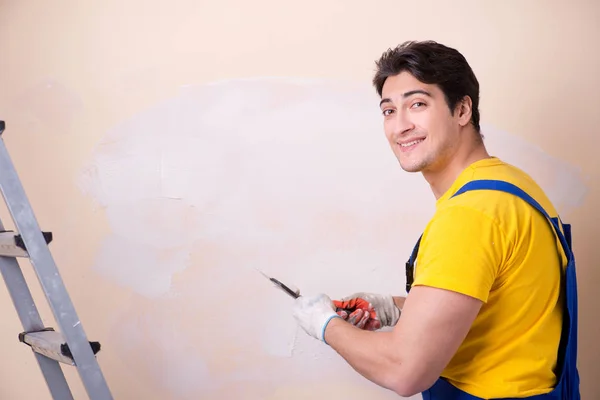 Empleado joven contratista aplicando yeso en la pared — Foto de Stock