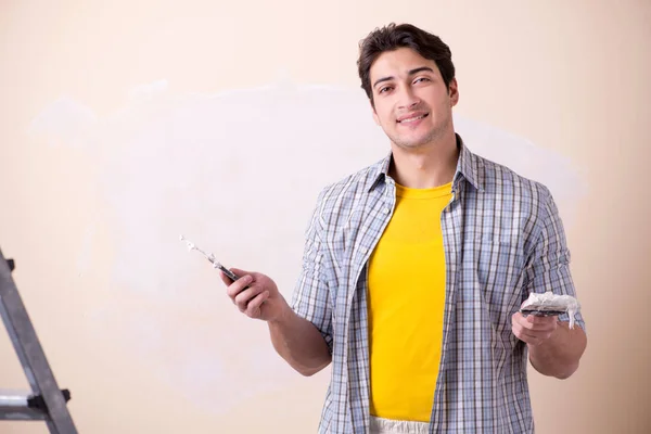 Young man applying plaster on wall at home — Stock Photo, Image