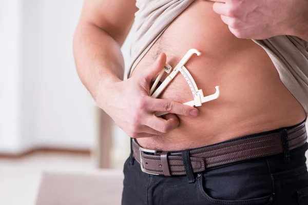 Hombre midiendo grasa corporal con pinzas — Foto de Stock