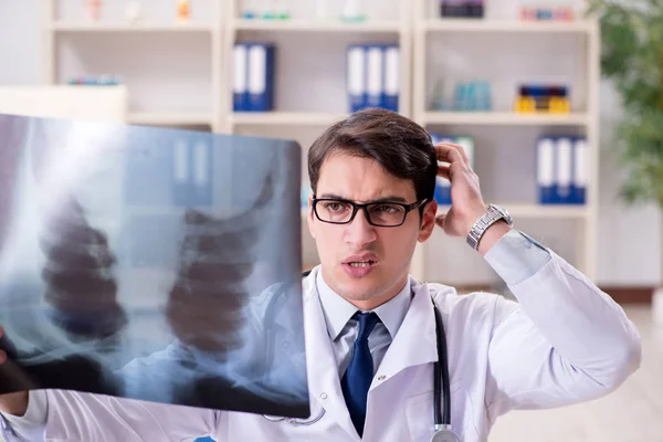 Médico joven mirando imágenes de rayos X en la clínica —  Fotos de Stock