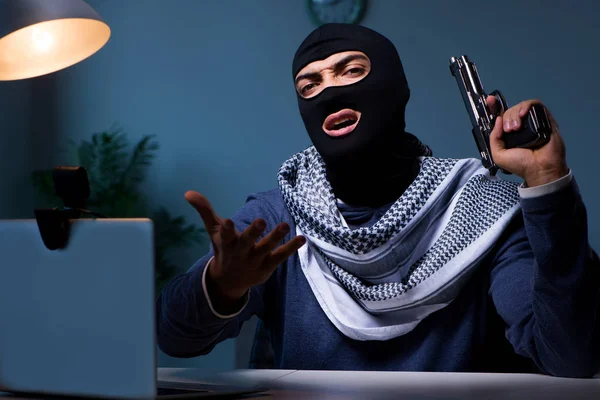 Terrorist burglar with gun working at computer