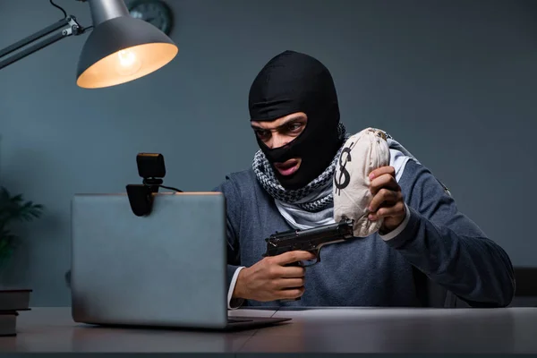 Terrorist burglar with gun working at computer