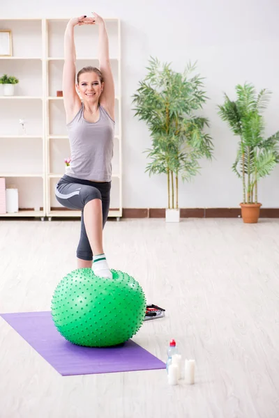 Giovane donna che si allena con palla di stabilità in palestra — Foto Stock