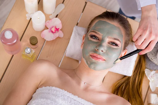 Mujer joven en concepto de salud spa con mascarilla facial — Foto de Stock