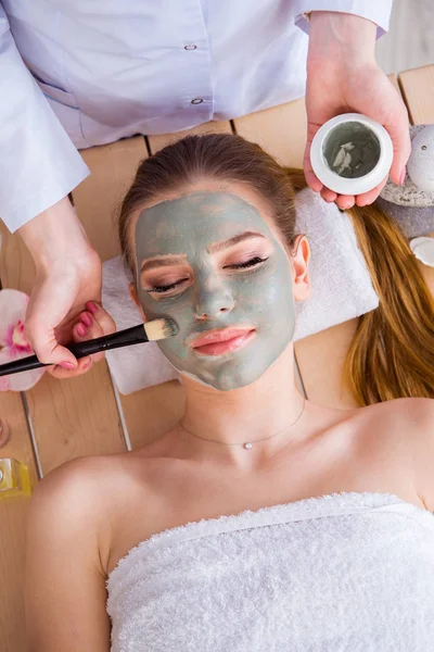 Mujer joven en concepto de salud spa con mascarilla facial — Foto de Stock