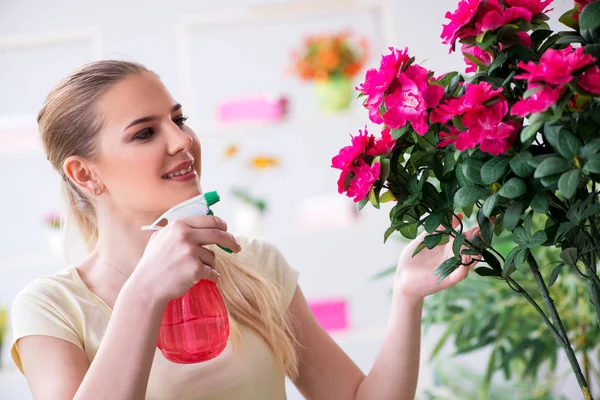 Jonge vrouw water geven planten in haar tuin — Stockfoto