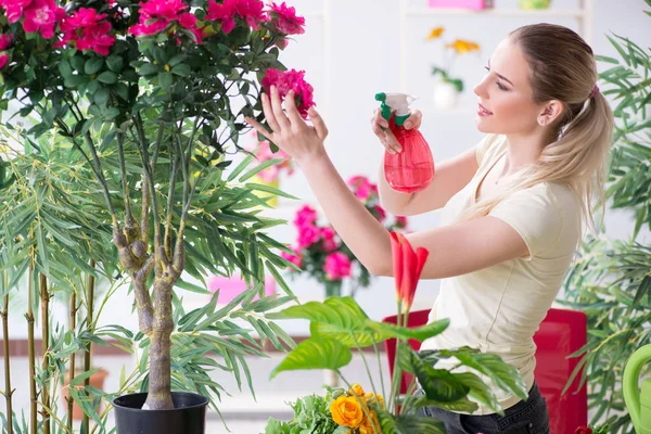 Jonge vrouw water geven planten in haar tuin — Stockfoto