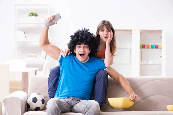 Jovem assistindo futebol com sua esposa em casa — Fotografia de Stock