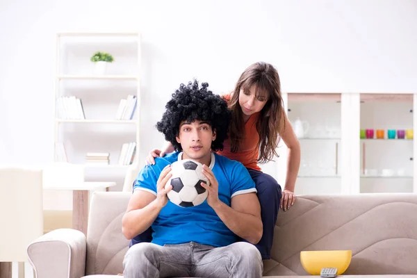Jovem assistindo futebol com sua esposa em casa — Fotografia de Stock